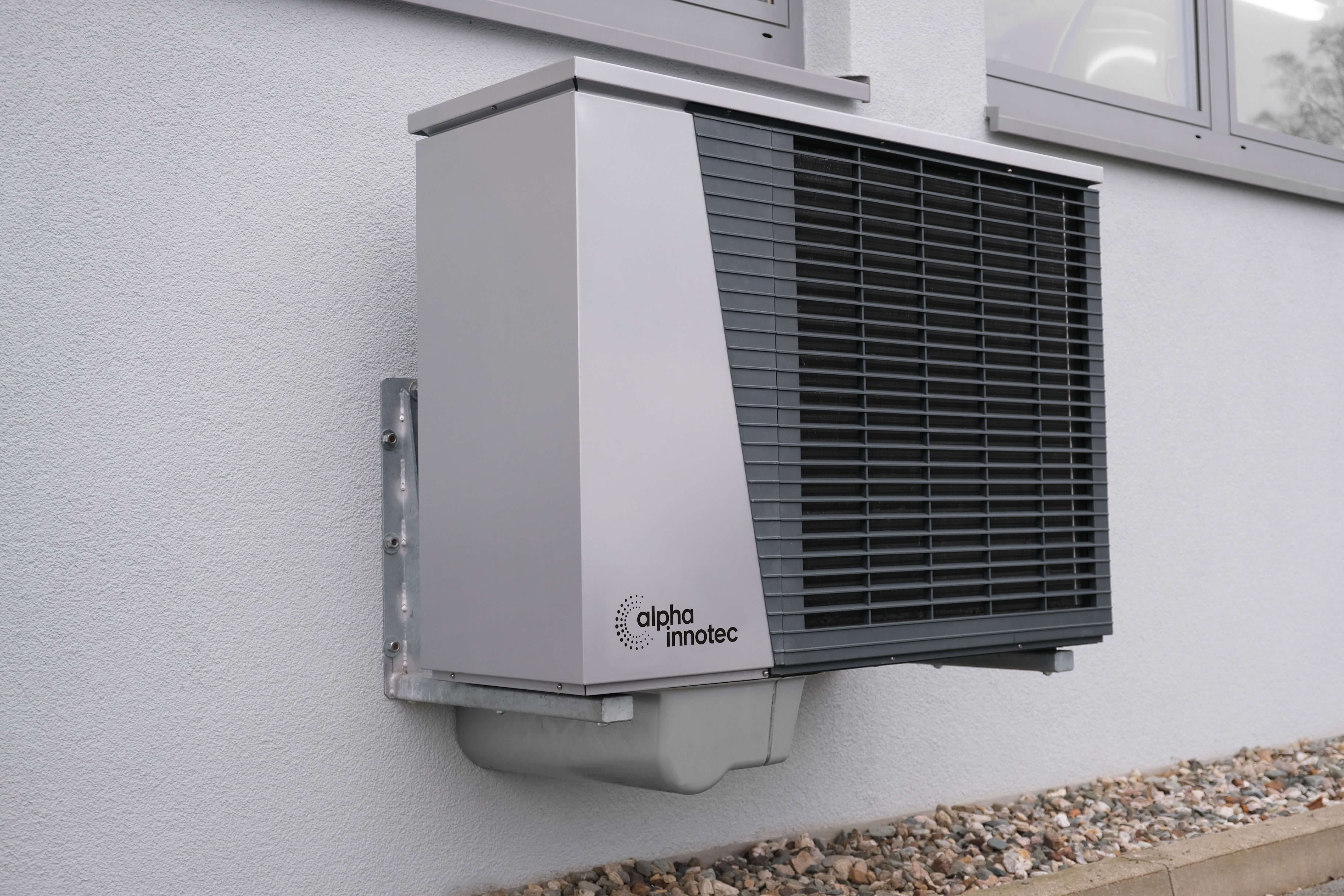 Heat pump condenser mounted on building exterior